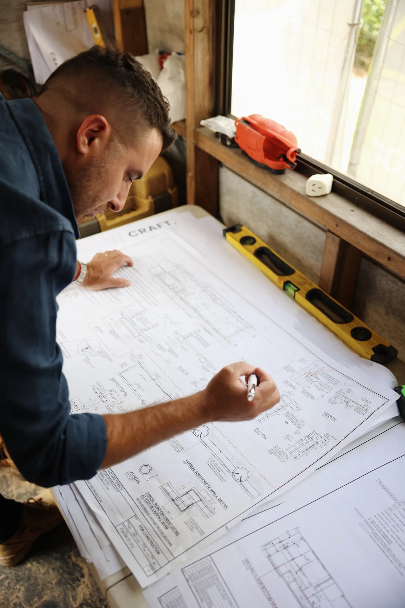 A builder marking up construction plans on a workbench during a StoryRocket shoot.