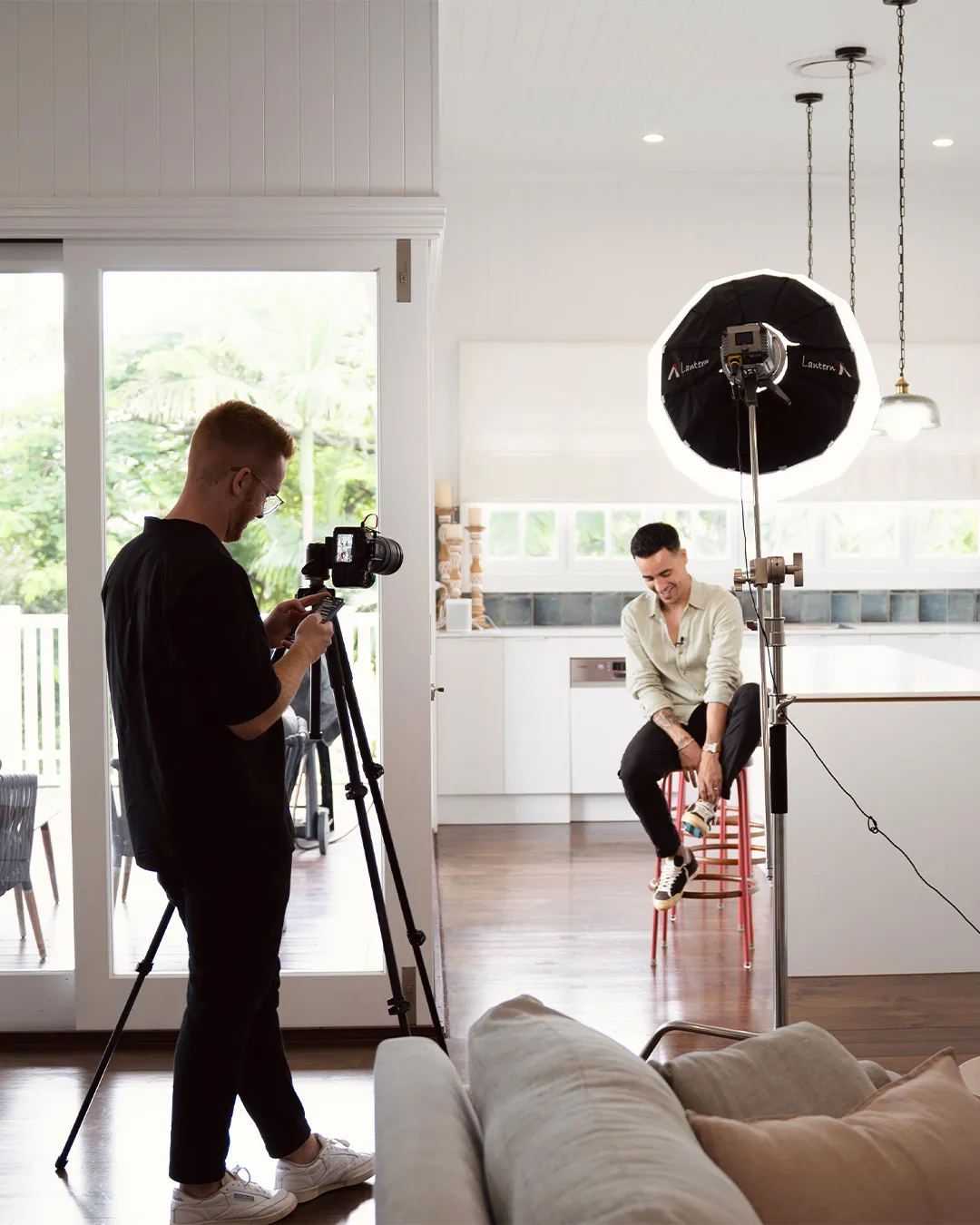 Jethro filming a client seated in their kitchen on a StoryRocket shoot day.